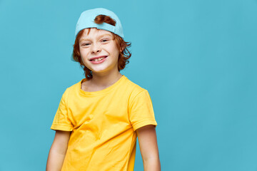 Joyful red-haired boy with a cap on his head yellow t-shirt childhood 