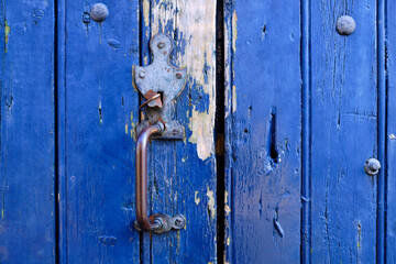 Old metal rustic door handle on a blue wooded door close up of the vintage feature