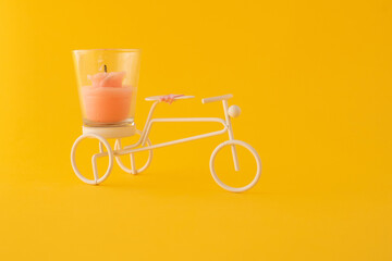 Decorative miniature little metal bicycle with candle isolate on orange background