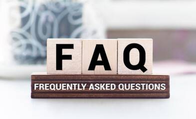 FAQ word on wooden block on top of wooden background.