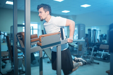 young athletic male has personal workout and pull up on bar in gym