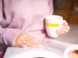 Close up hand woman on book with blur image of holding white coffee mug. woman life style at home on holiday her reading a book.