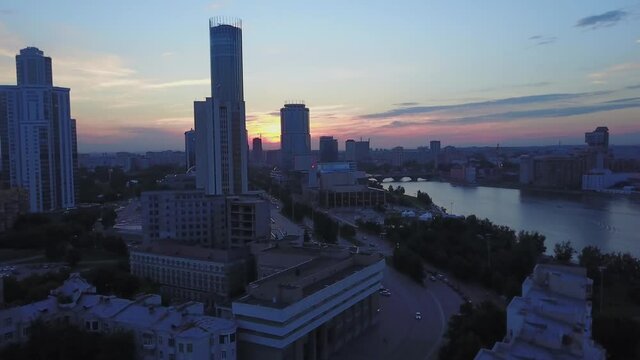 Aerial view of sunset above the skyscrapers and other buildings. Stock footage. Late evening in a sunny modern city district.