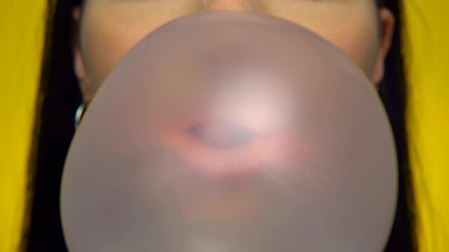 Woman blowing bubble gum, pop it. Bubble gum stuck on nose, loser