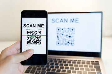 Using a smartphone app to scan a QR code.  Man's hand uses a mobile phone application to scan QR codes in online stores that accept digital payments without money. Cashless technology concept.