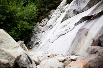 young boy climing up a granite cliff while on a hike