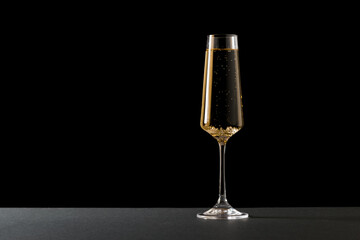 A glass filled with champagne on a black background.