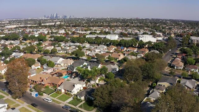 Aerial descending shot of a South LA neighborhood with Downtown Los Angeles in the background. HD at 60 FPS.