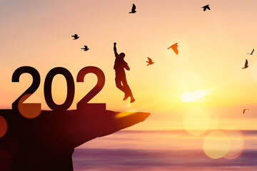 Silhouette man jumping and birds flying on sunset sky tropical sunset beach and number like 2021 abstract background. Happy new year and holiday celebration concept.