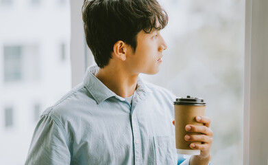 Asian businessman is drinking coffee by the window