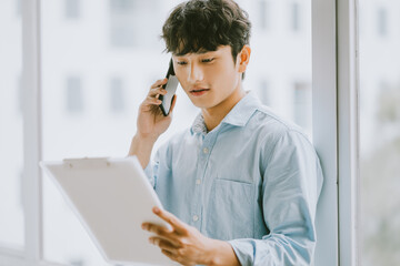 Asian businessman is calling to discuss about the work by the window