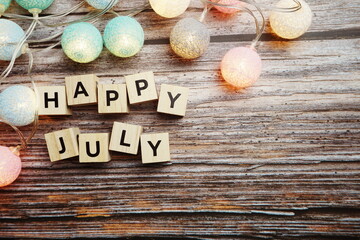 Happy July alphabet letter with LED Cotton ball Decoration on wooden background