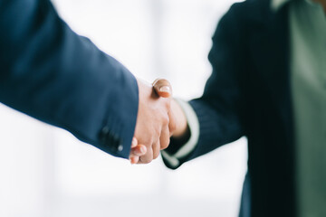 Two young Asian businessmen shake hands after signing a contract