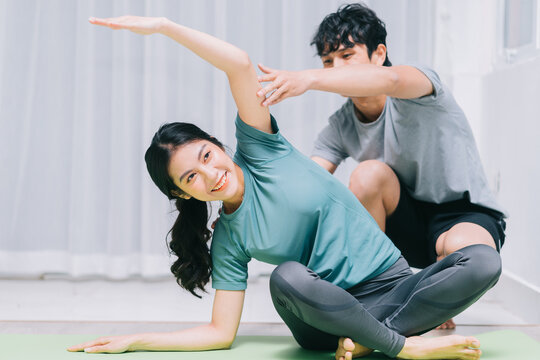 Asian couple doing yoga together at home