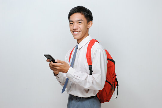 Senior High School Student Of Indonesia With Uniform Holding Mobile Phone Smiling Looking At The Camera