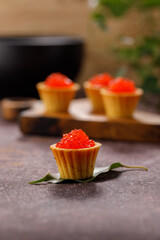 Appetizing tartlets with red caviar on a decorative board for serving. Holiday concept. Close-up.