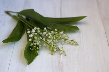 bouquet of lilies of the valley on a light wooden background