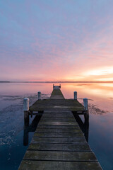 Purple sunrise sky over wooden jetty on the lake.