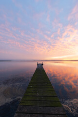 Colorful sunrise cloud over a wooden jetty on the lake.