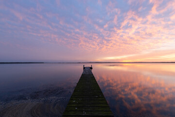 Fototapeta na wymiar Colorful sunrise cloud over a wooden jetty on the lake.