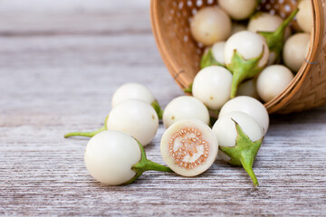 Selective focus. Thai white eggplant in wooden basket on wood table background.