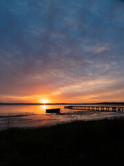 Fototapeta na wymiar Boat and jetty silhouette on the lake side during sunrise.