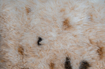 Background made of textured fabric in the form of artificial fluffy animal hair with black and brown spots of abstract pattern