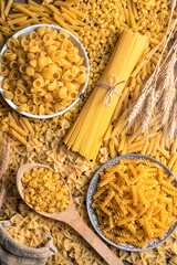 A large assortment of pasta on the table. Top view, vertical orientation. Culinary background. The concept of food.