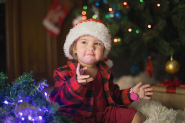 Fototapeta na wymiar a child in red clothes is sitting waiting for the new year. the concept of celebrating Christmas at midnight. holiday costume