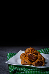 Put the chocolate filling cream in a white plate on top of a green patterned cloth set on a cement table.
