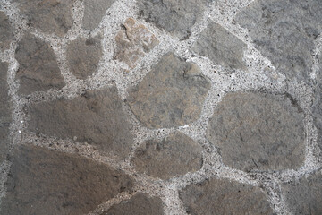 Stone pavement. Texture of stone paved ground. Large jagged stone blocks on a pedestrian sidewalk or road. Ancient masonry. Great for background and design.