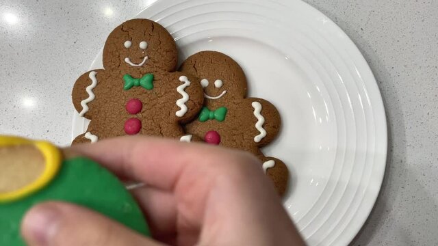 Child taking a bite out of a colorfully decorated holiday cookie shaped into a Christmas ornament.