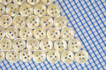 Obraz premium Plastic shiny buttons for clothes on a fabric background. Fashion and clothing. Factory industry
