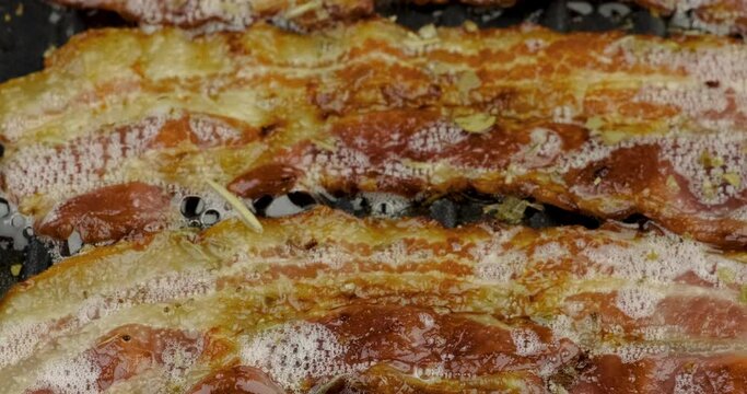 Truck shot close up of crispy bacon frying grill with bubble oil on non-stick enamel pan grill