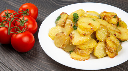 cooked fried potatoes with herbs and vegetables in a white plate on a wooden table