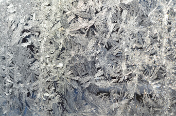 Frost patterns on the frozen window. Hoarfrost background, frost texture, Christmas pattern on winter window glass. Backdrop for Christmas and New Year.