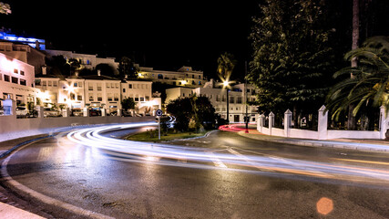 Long exposure night photo of a road curve with car trails, in a town of Andalusia.