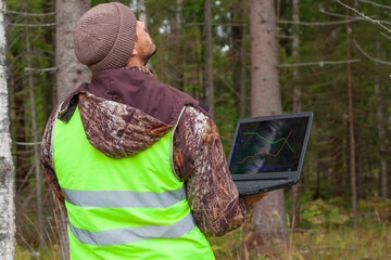 Ecologist works in the forest with a computer.