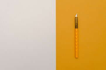 Stationery paper knife on blank colored paper. Place for text. Top view.