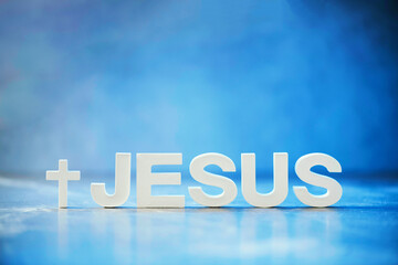 Name JESUS made with cement letters on blue light marble background. Copy space. Biblical,...