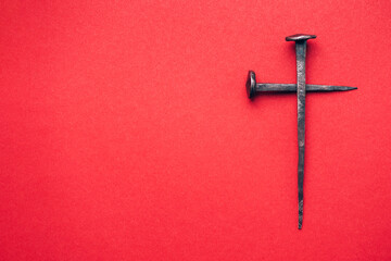 Cross made with rusty nails and drops of blood on red background. Copy space. Good Friday, Easter...