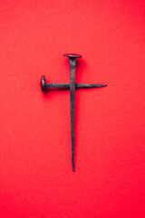 Cross made with rusty nails and drops of blood on red background. Copy space. Good Friday, Easter...