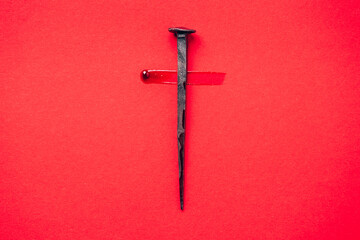 Christian cross made with rusty nails, drops of blood on red background. Copy space. Good Friday, Easter day. Christian backdrop. Biblical faith, gospel, salvation concept. Jesus Christ Crucifixion