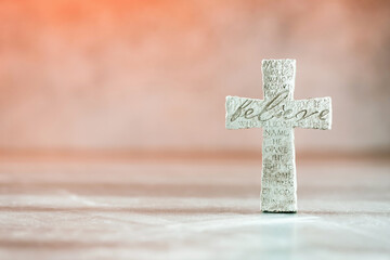 Stone cross with inscription Believe on grey background, Copy space. Christian backdrop. Biblical faith, gospel, salvation concept