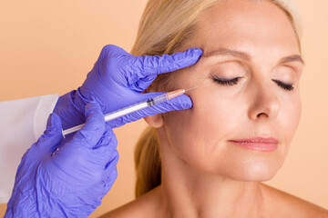 Close up photo middle aged woman undergo plastic surgery doctor make injection with syringe...