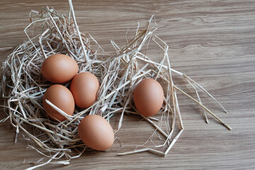 The eggs in a straw were laid on a wooden table.