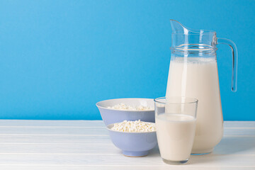 Glass pitcher of milk and bowl of cottage cheese on wooden table
