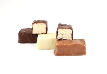 Small italian Torrone, or nougats, covered with milk, dark and white chocolate on a white background.