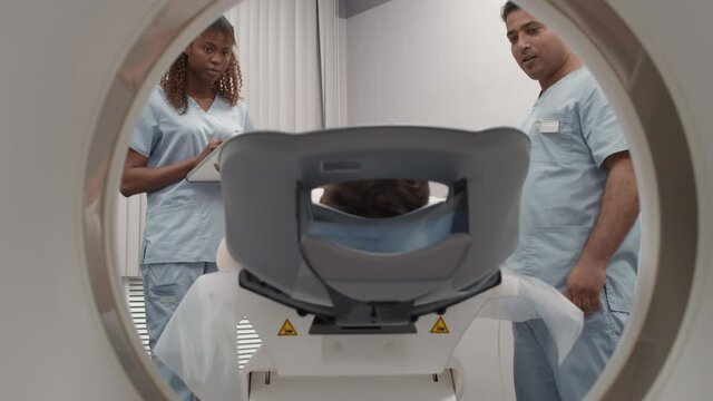 Slowmo shot of multi-ethnic radiologists performing CT scan of patient in hospital