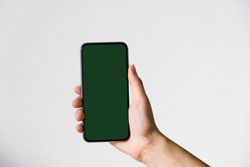 Hand holding white mobile phone with blank white screen in white background.